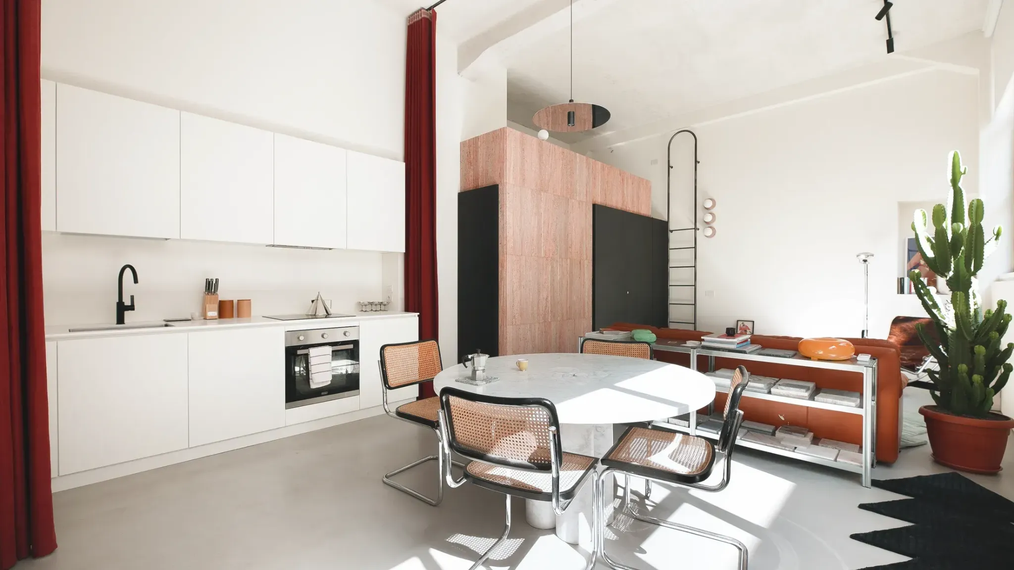 Кухня гостиная с белыми шкафами красными шторами и обеденным столом 5 Bold Design Ideas Inside a Small Milan