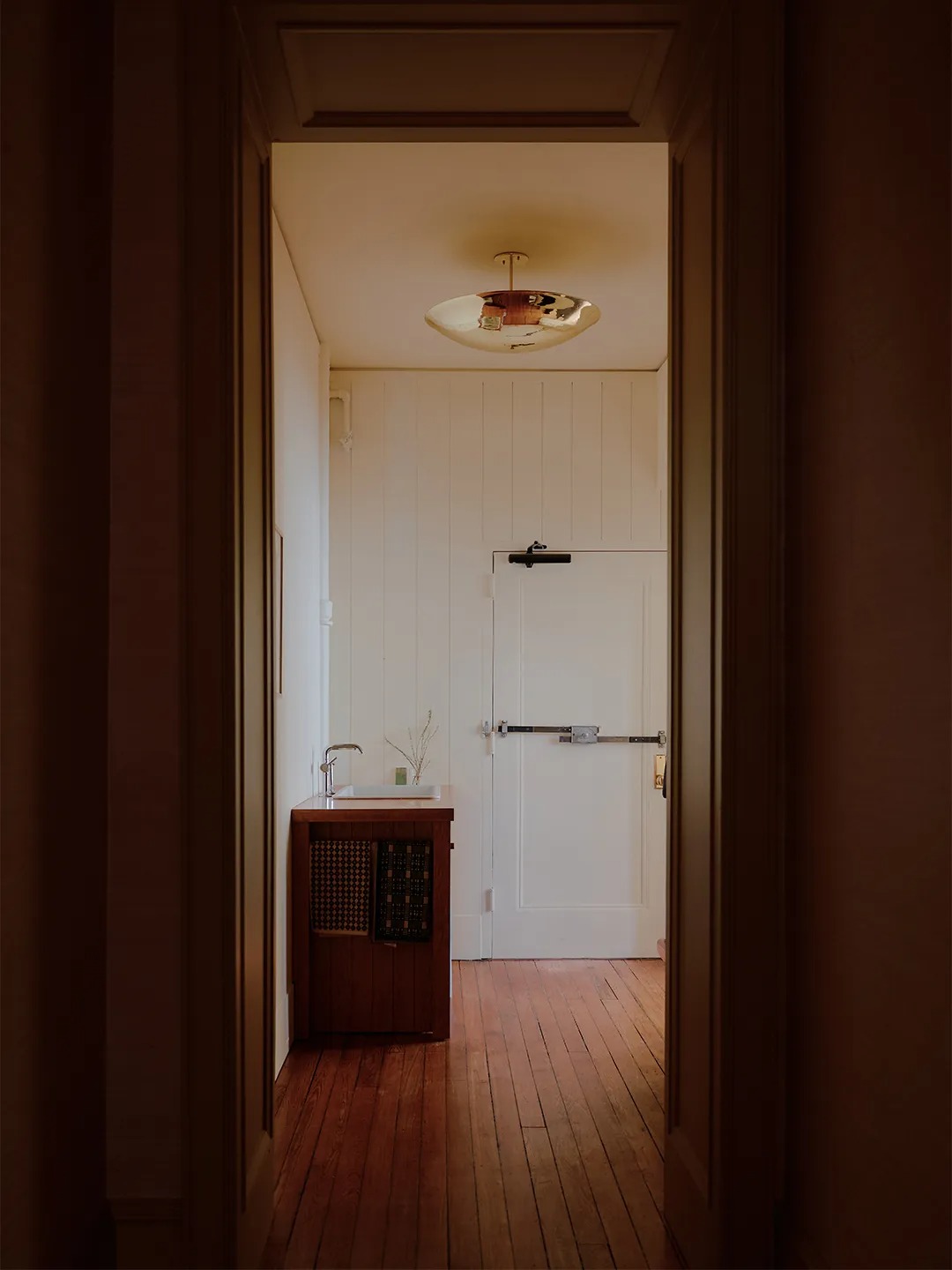 Узкий коридор с раковиной и белой дверью Mismatched Doorknobs and Crimson Floors