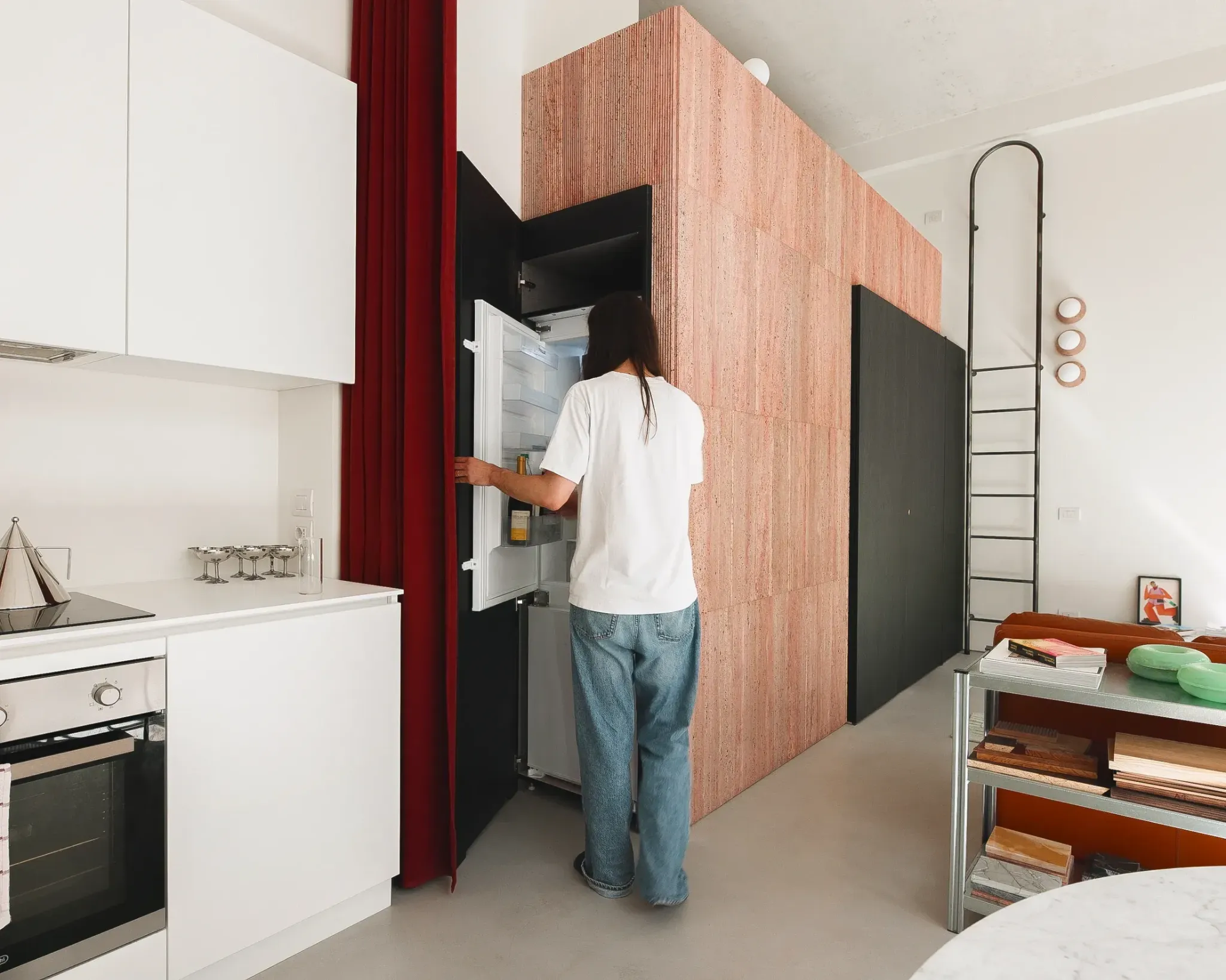 Человек открывает холодильник в кухне с красными шторами 5 Bold Design Ideas Inside a Small Milan