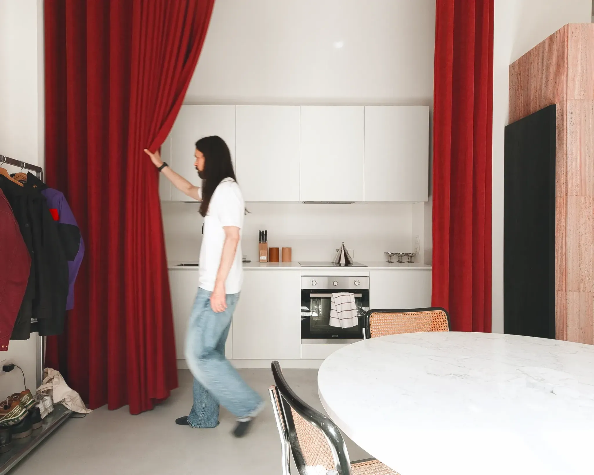 Человек раздвигает красные шторы в кухне 5 Bold Design Ideas Inside a Small Milan